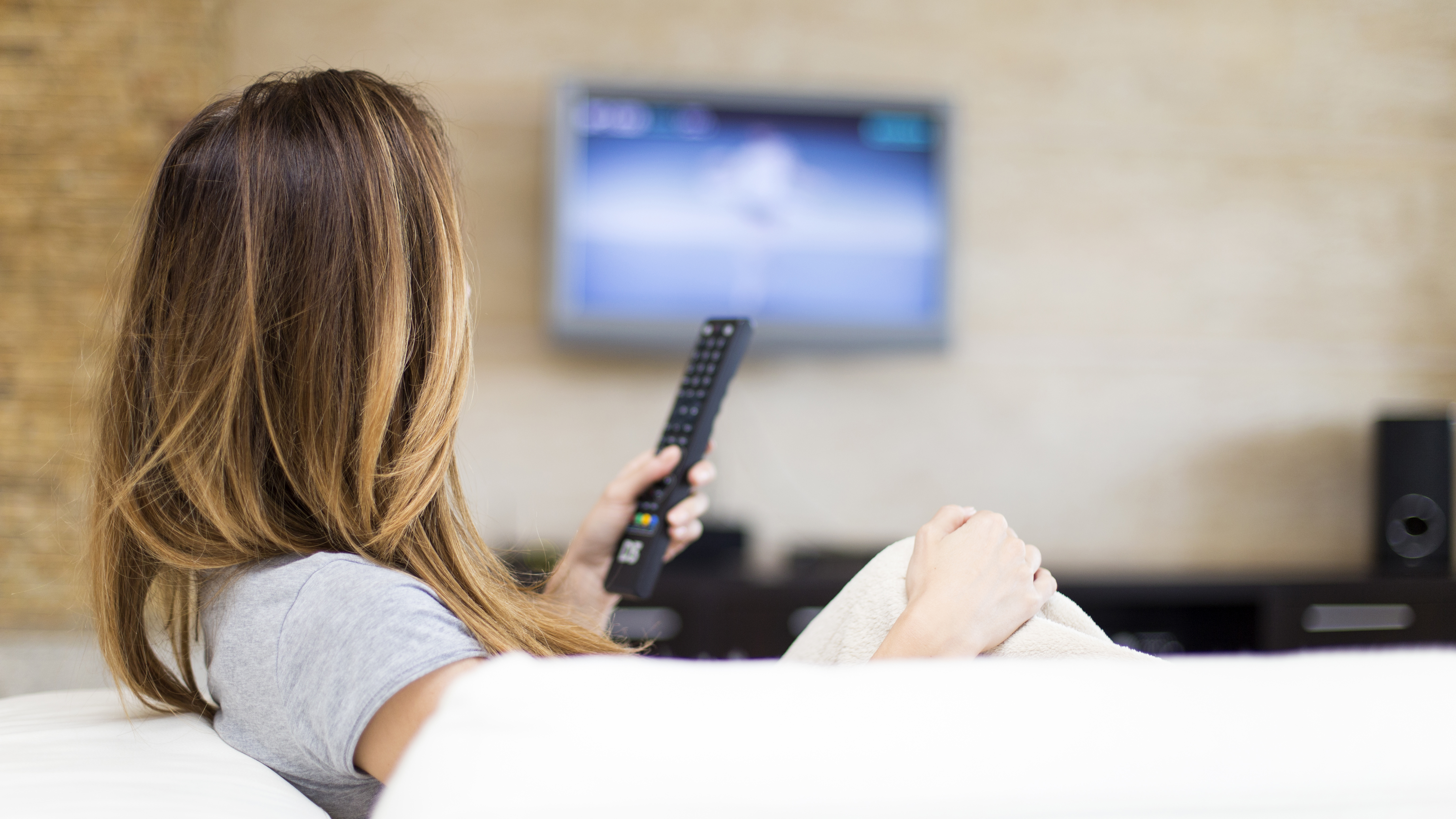 ragazza seduta sul divano che guarda la tv